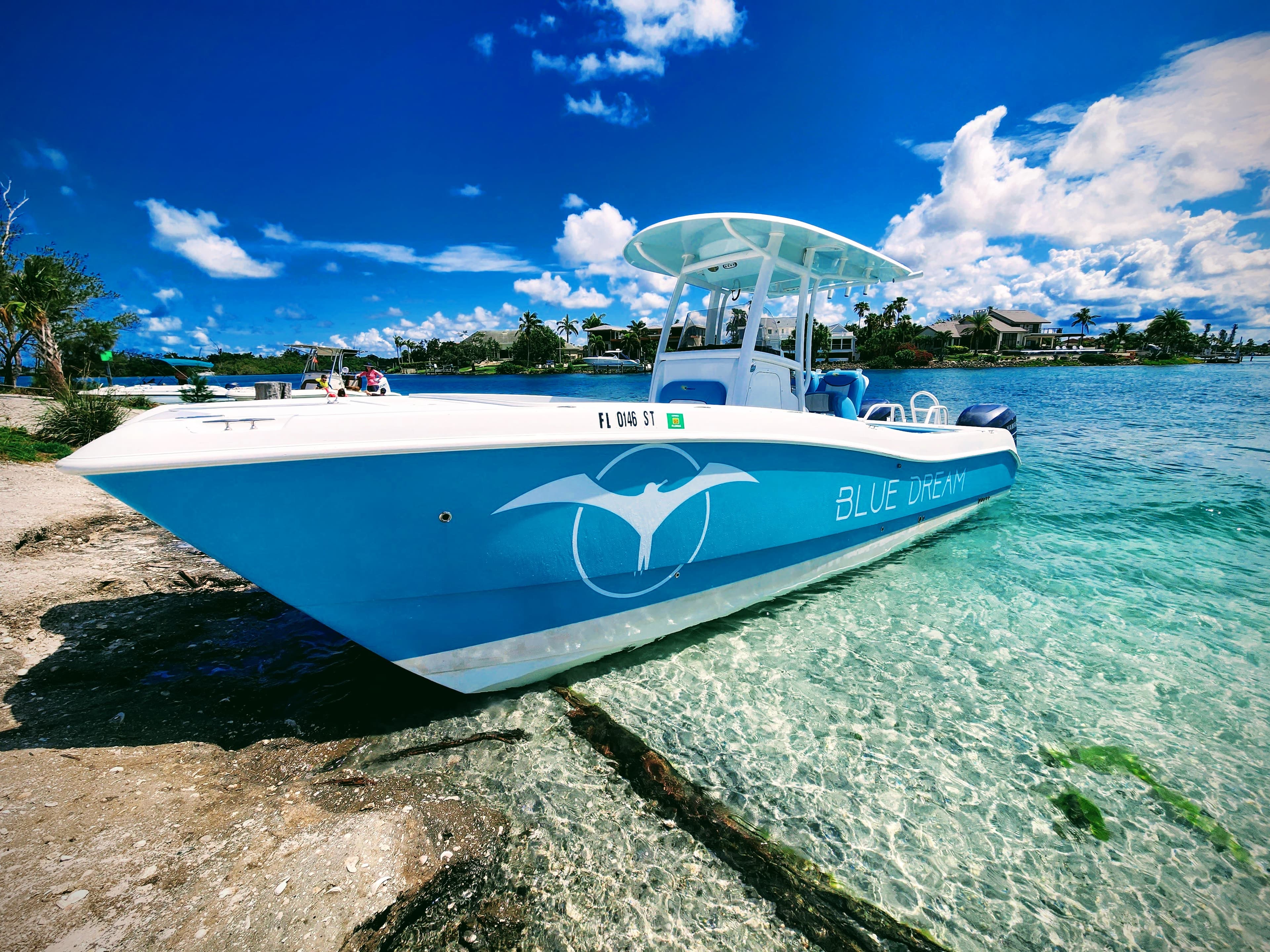 Aquaholic Charters' boat beached at the Venice jetty, turquoise water and beachfront homes behind it